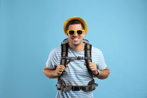 Male tourist with travel backpack on turquoise background - Фото, изображение