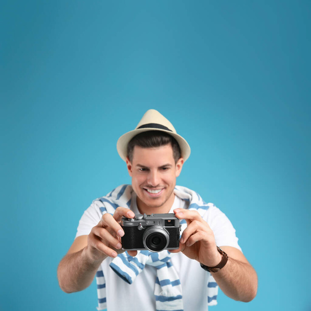 Male tourist taking picture against turquoise background, focus on camera - Fotó, kép