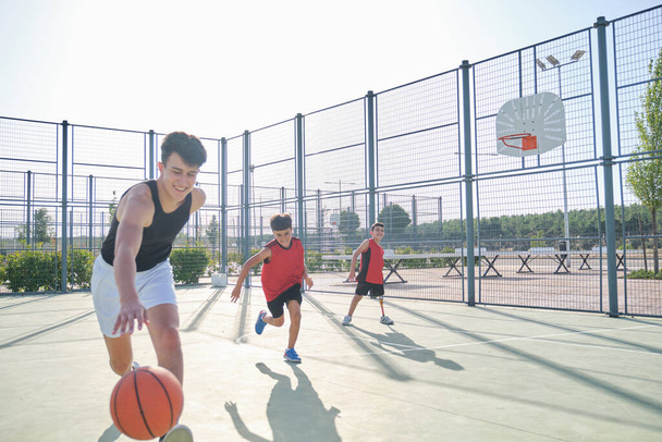 Tres hermanos jugando baloncesto, uno de ellos tiene una prótesis de pierna. Hermanos jugando al basket. - Foto, imagen