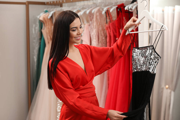 Woman choosing dress in rental clothing salon - Foto, Imagen