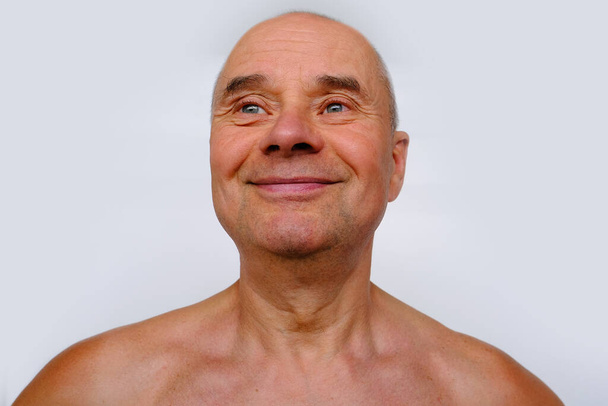close-up face of elderly bald tanned man 60 years old with a naked torso looking, smiling, wrinkles and age spots, aging problems, concept of male age, midlife crisis - Foto, Bild
