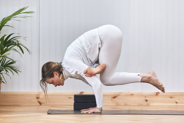 женщина, одетая в спортивное постельное белье, делает позу крана для йоги - Фото, изображение