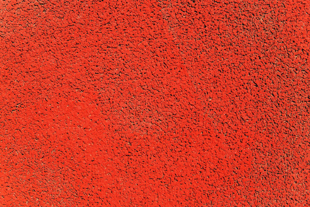 Background and texture of the sports field coating. Artificial material of orange color. Uneven rough surface. - Photo, Image