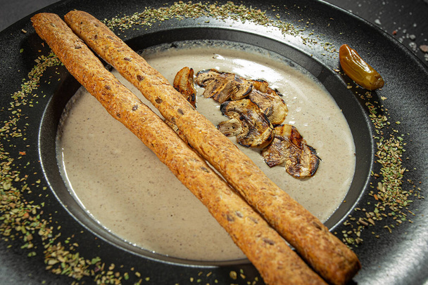mushroom soup in a black bowl, champignons, bread sticks and sour cream - Photo, Image