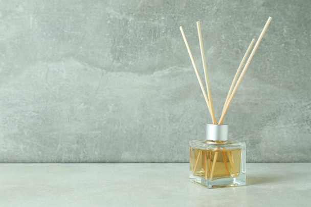Diffuser bottle with sticks against gray textured background - Photo, Image