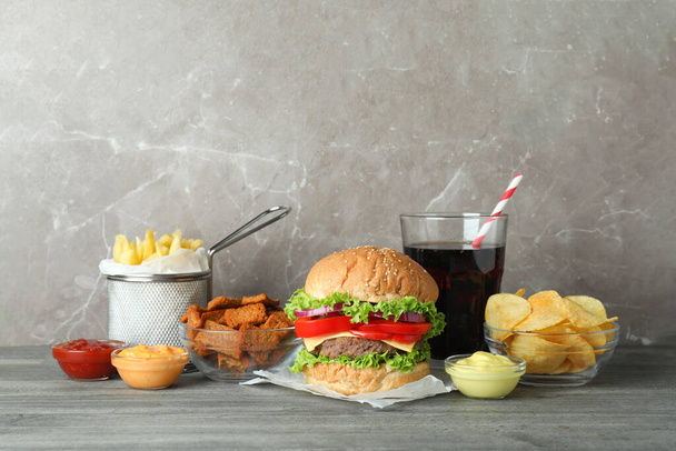 Tasty fast food on gray textured table - Fotoğraf, Görsel