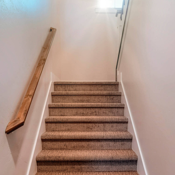 Escalier carré à l'intérieur de la maison avec rampe murale en bois et tapis sur les marches - Photo, image