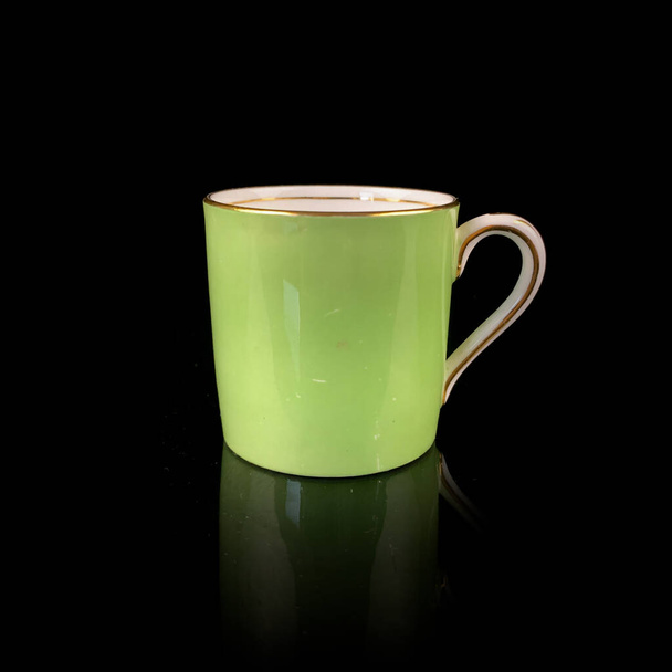 Porcelain antique green cup with saucer. vintage hand painted ceramic tea set. floral pattern on a black background - Fotó, kép