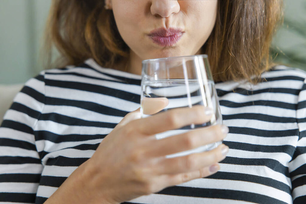 Young woman gargling while using mouthwash from a glass - Fotó, kép