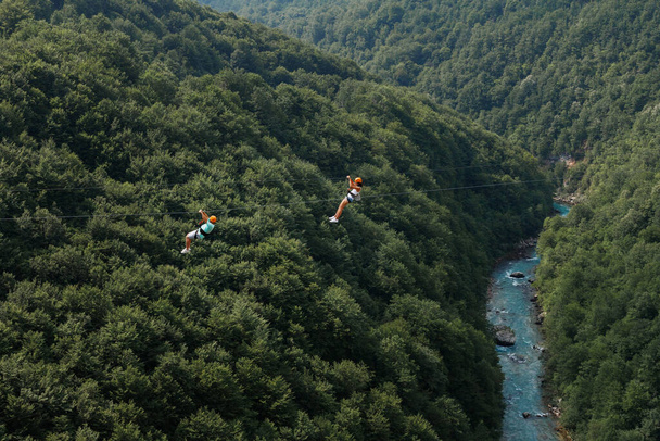 İki turist yeşil dağların ve nehirlerin arka planında bir halat hattında - Fotoğraf, Görsel
