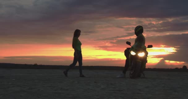 Couple embrassant près de moto sur la plage au coucher du soleil - Séquence, vidéo