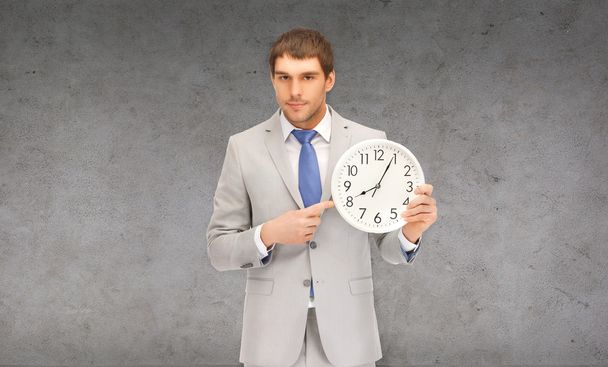 handsome businessman pointing finger to wall clock - Foto, imagen
