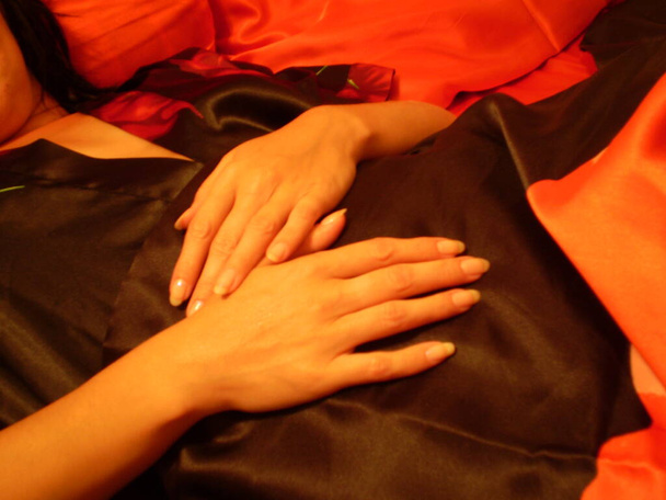 Γυναίκα με μεταξωτό φόρεμα δείχνει τα πόδια και τα χέρια της - Φωτογραφία, εικόνα