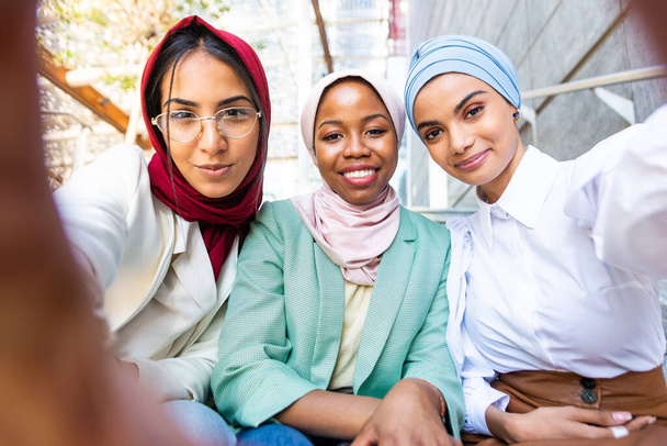 カジュアルな服と伝統的なヒジャーブのボンディングを身に着けているイスラム教徒の女の子の多民族グループと楽しい屋外で- 3アラビア語の若い女の子 - 写真・画像