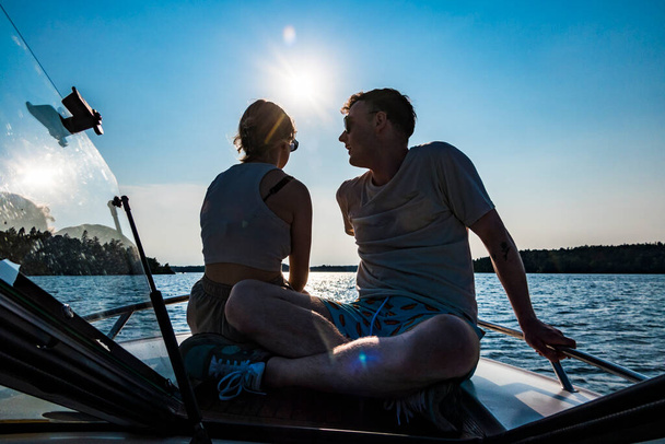 Stockholm, Schweden ein junges Paar zusammen auf dem Bug eines Motorbootes bei Sonnenuntergang. - Foto, Bild