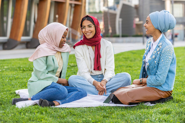Multiethnic group of muslim girls wearing casual clothes and traditional hijab bonding and having fun outdoors - 3 arabic young girls - Fotó, kép