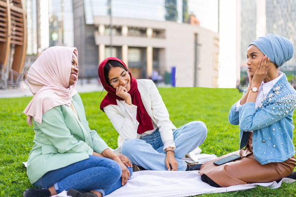 Multiethnic group of muslim girls wearing casual clothes and traditional hijab bonding and having fun outdoors - 3 arabic young girls - Foto, afbeelding