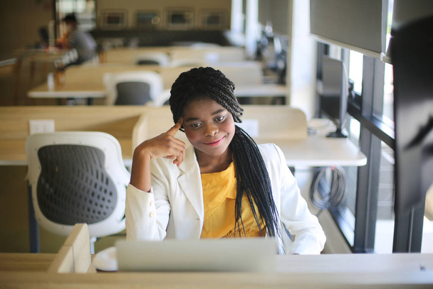 Joven mujer afroamericana trabajando con computadora portátil concentrado y sonriente. - Foto, Imagen