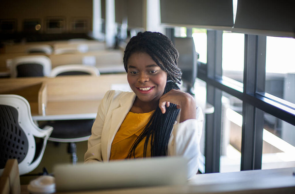 Joven mujer afroamericana trabajando con computadora portátil concentrado y sonriente. - Foto, imagen