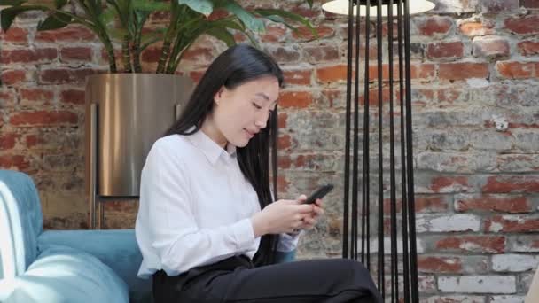 Asian Business Woman standing in restaurant browsing her Phone Social Networks. - Imágenes, Vídeo