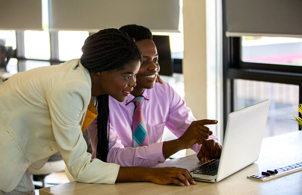Dos empresarios afroamericanos discutiendo y concentrados en la computadora portátil en la reunión. - Foto, imagen