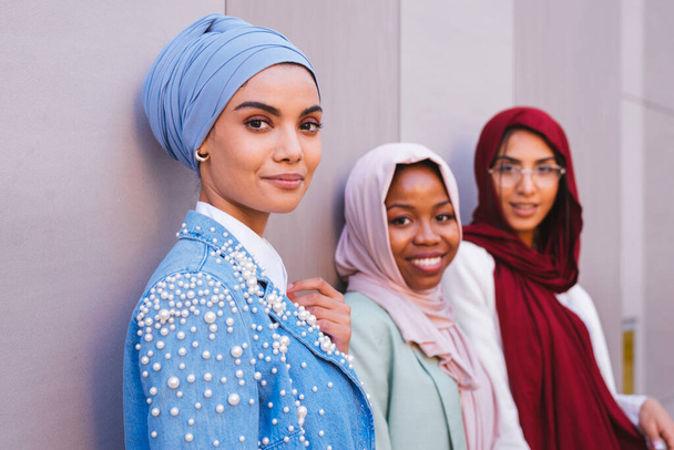 Multiethnic group of muslim girls wearing casual clothes and traditional hijab bonding and having fun outdoors - 3 arabic young girls - Foto, imagen