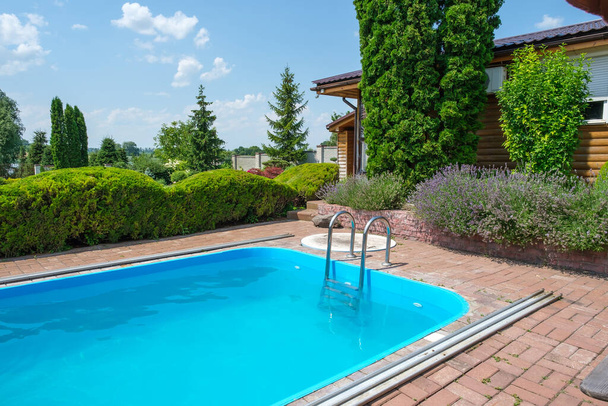 Schwimmbad und Garten mit schön beschnittenen Sträuchern und Steinen im Hinterhof. - Foto, Bild