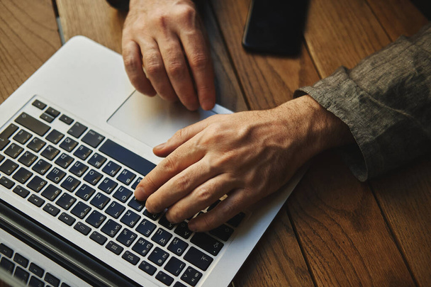  Yüzü olmayan bir adamın elleri, bilgisayarda çalışıyor. en üstteki görünüm. - Fotoğraf, Görsel