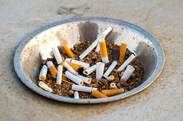 通りに金属灰皿のタバコの吸い殻を閉じます。喫煙後の多くのタバコの破片の概念.  - 写真・画像