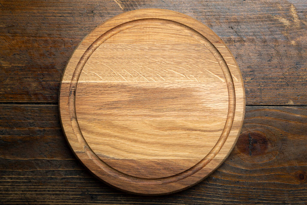 Empty round cutting board on a wooden table. Space for text. Top view. - Foto, imagen