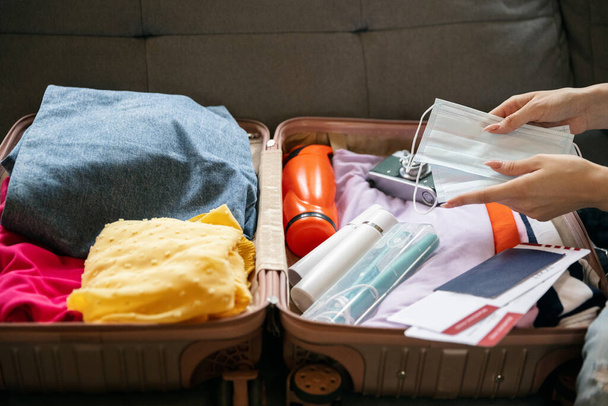 Close-up female hands packing suitcase for summer vacation, holiday at home interior, indoors. Concept of fashion, beauty, lifestyle, lesuire activity. - 写真・画像