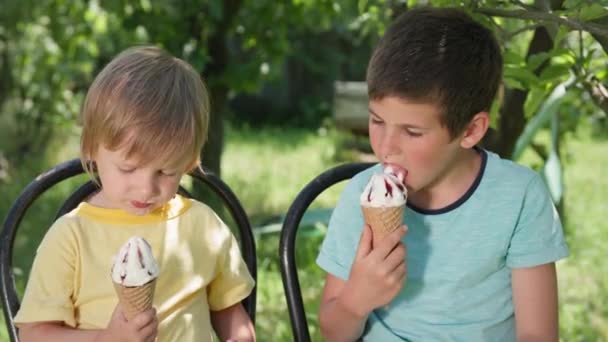 όμορφα αρσενικά παιδιά με απόλαυση γλείφουν τη γλώσσα τους σε δροσερό παγωτό κατά τη διάρκεια των καλοκαιρινών διακοπών viema και δείχνουν τα δάχτυλά τους επάνω - Πλάνα, βίντεο