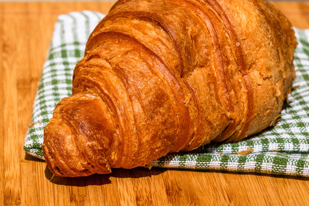 Friss croissant részletek a fa asztalon. Étel és reggeli koncepció. Közelkép a francia vajas croissant - Fotó, kép