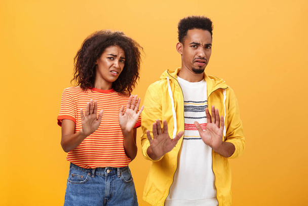 Two african american stylish friends hanging around interrupted by weird guy offering strange proposal shaking hands near chest in refusal and rejection gesture grimacing from aversion and dislike - Photo, Image