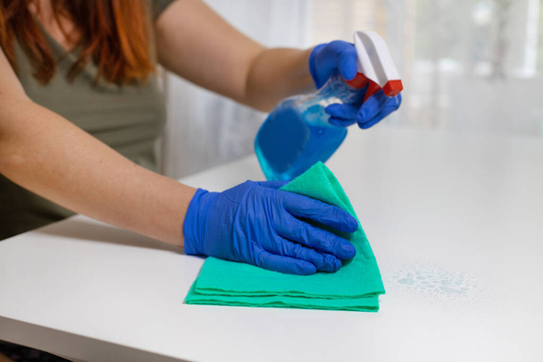 Mesa de limpieza mujer con spray desinfectante de color azul y toalla amarilla. COVID-19 prevención desinfectante interior - Foto, imagen