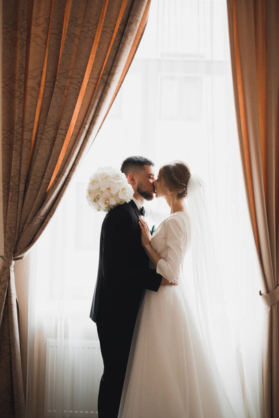 Schöne Braut und Bräutigam umarmen und küssen sich am Hochzeitstag - Foto, Bild