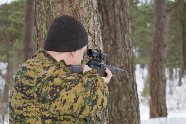 Hunter takes aim from behind a tree - Photo, Image