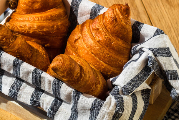 Friss croissant, puff tészta és vajas francia croissant fából készült ládán. Étel és reggeli koncepció. Desszertek és friss péksütemények részletes leírása - Fotó, kép