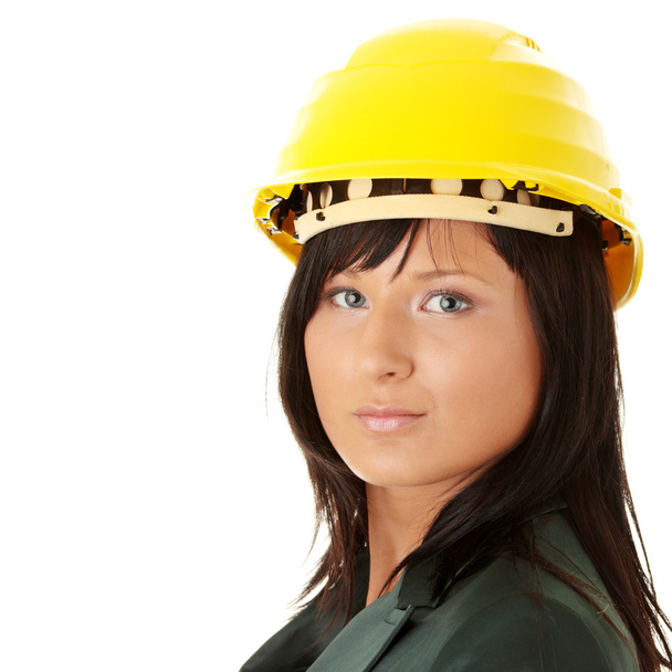 Young female architect or builder wearing a yellow hart hat on a construction site - Foto, Imagen