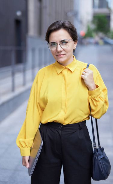 Portret van een zakenvrouw met laptop op zoek naar camera - Foto, afbeelding