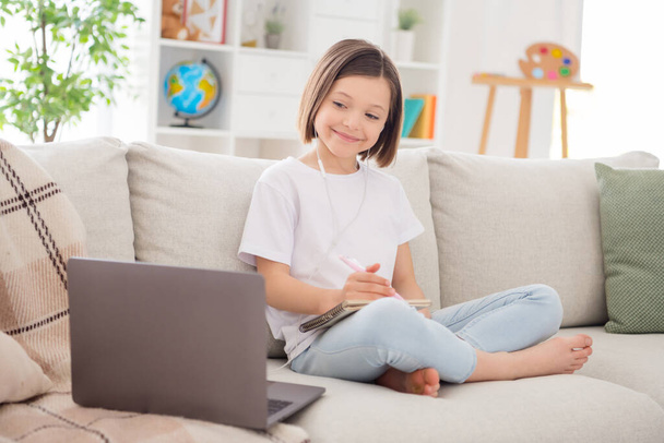 Full size profil strona zdjęcie młodej szkoły dziewczyna szczęśliwy uśmiech słuchać słuchawki lekcja laptop odległość edukacja pisać notatki do domu - Zdjęcie, obraz