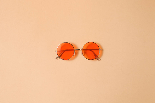 Minimal style. Minimalist fashion photography. Vintage. Glamour. Red sunglasses on pastel brown backgrounds. Flat lay. - 写真・画像