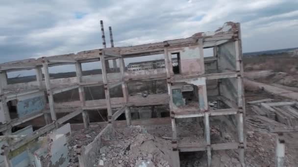 FPV drone vola rapidamente e manovrabile tra edifici industriali abbandonati e intorno a un escavatore. - Filmati, video