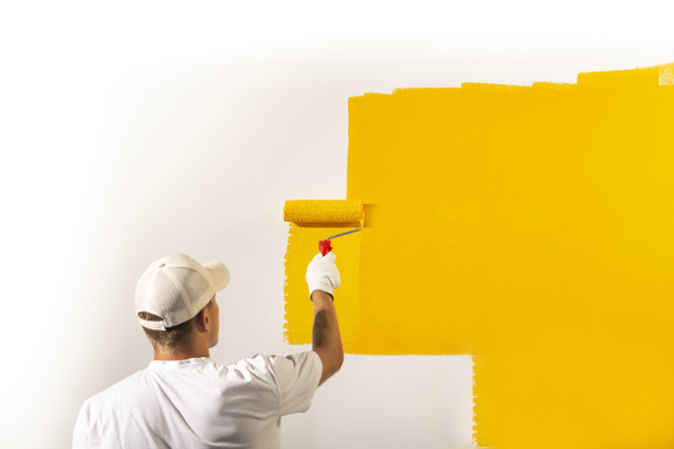Muž dekoratér malování stěny se žlutou barvou - Fotografie, Obrázek
