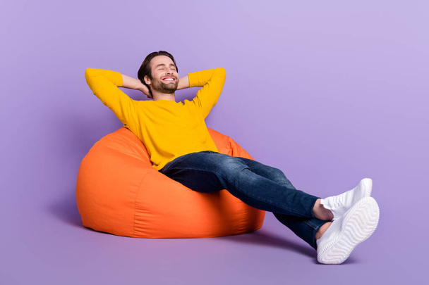 Full length body size photo smiling man laying in beanbag relaxing isolated pastel purple color background - Zdjęcie, obraz