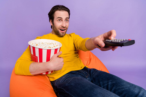 Portrait of attractive amazed cheerful man having fun eating corn watching tv series isolated over pastel violet purple color background - Foto, immagini