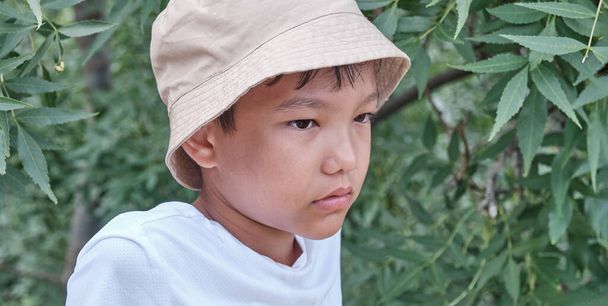 Asian boy in panama over background of green plants. - Zdjęcie, obraz