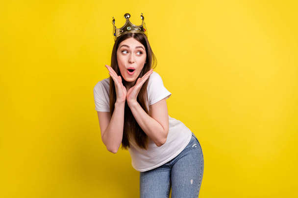 Photo of young excited girl happy positive smile look empty space wear golden crown isolated over yellow color background - Zdjęcie, obraz