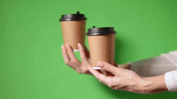 Два кофе специальное предложение или промо. Руки держат две чашки на желтом фоне экрана. Чай или кофе с собой. Бумажный стаканчик с черной крышкой. - Кадры, видео