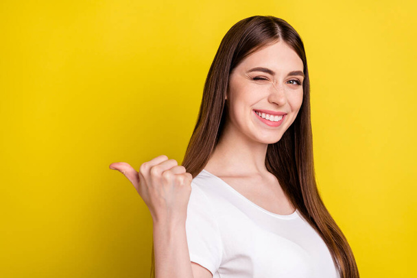 Photo portrait of woman showing blank space with thumb winking funky isolated vibrant yellow color background - Foto, afbeelding